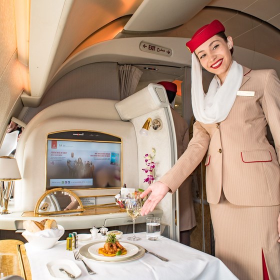 Flugbegleiterin mit Gourmet-Menü in der First Class